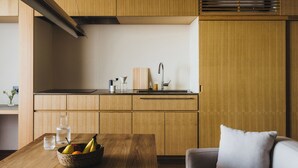 A modern kitchen with wooden cabinetry, a stainless steel sink, and a dining area with a table and a basket of fruit. - SANU 2nd Home Tateyama 1st (Tateyama)
