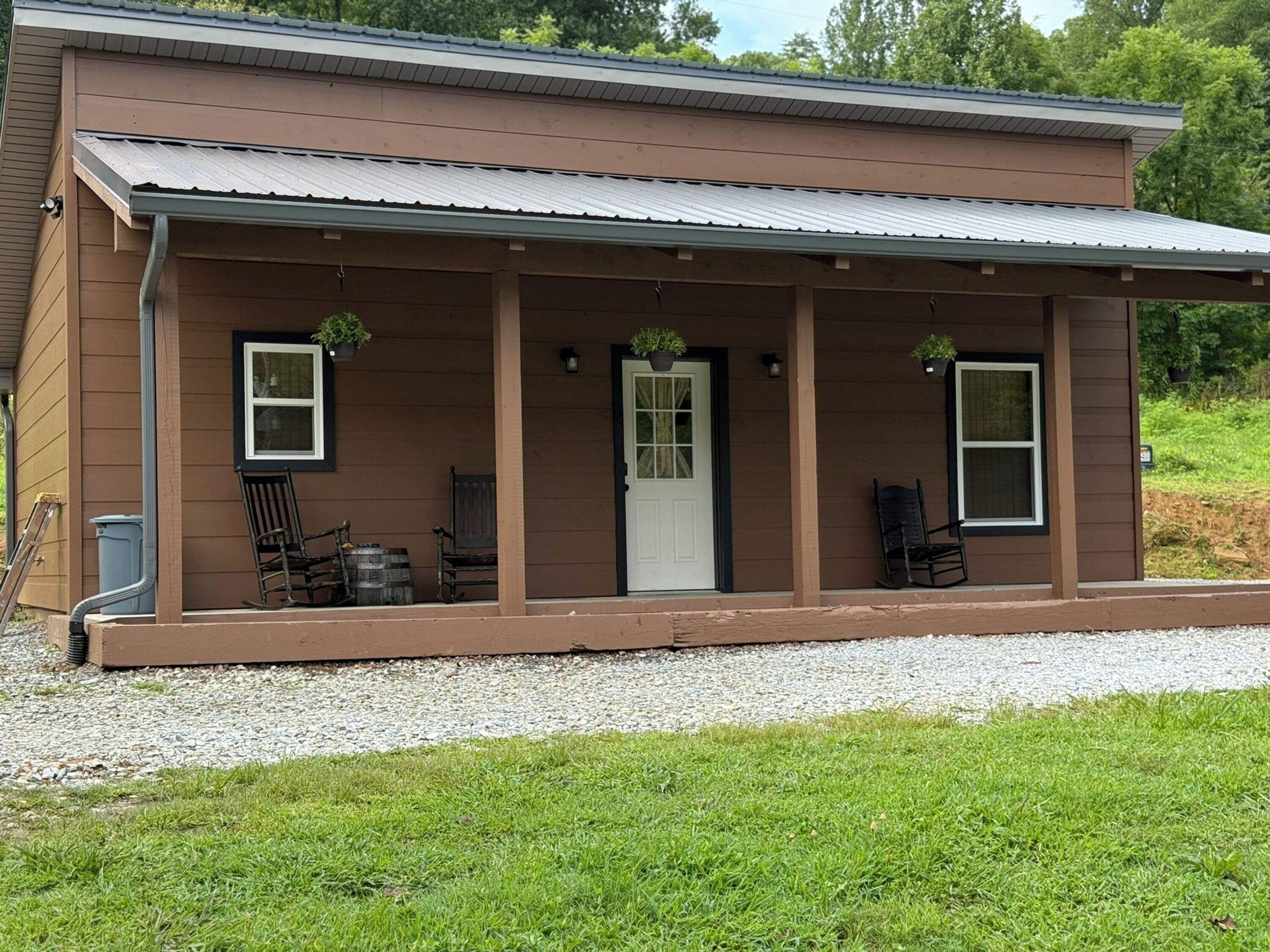A single-story house with a covered porch, a front door, and two windows.