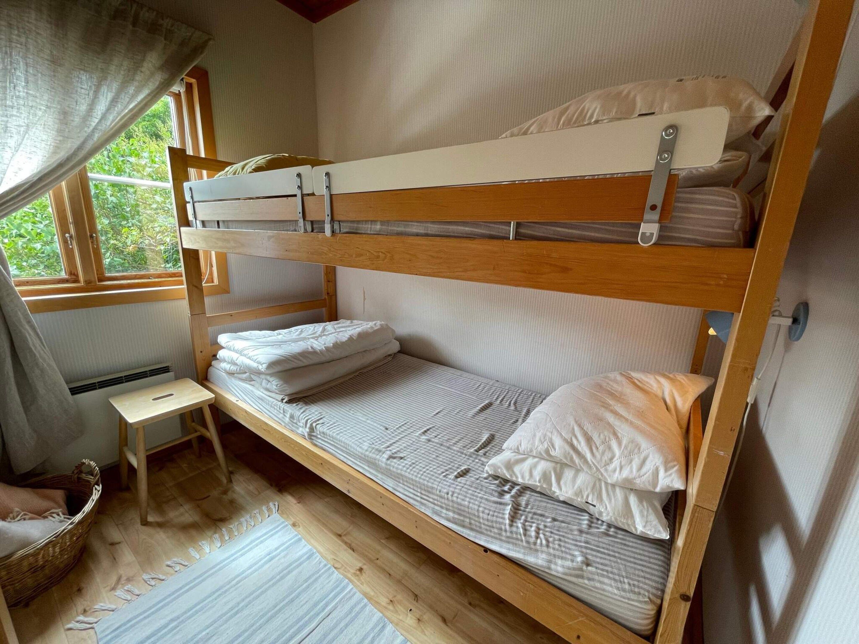 A bunk bed room with a small table and a window.