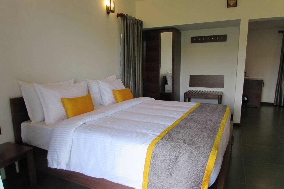 A neatly made bed with white and yellow pillows, a grey and yellow throw blanket, and a wooden headboard.