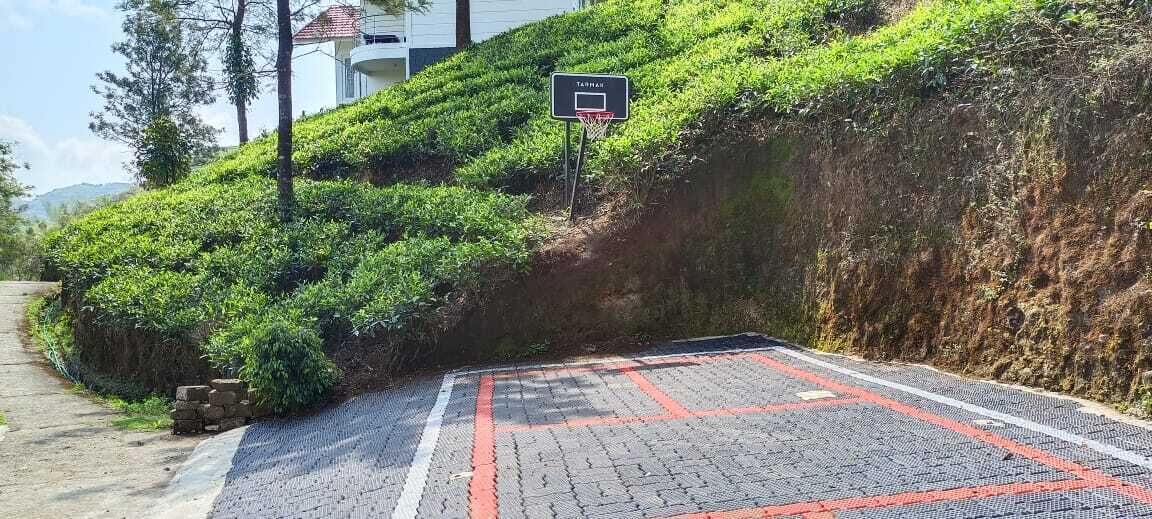A paved area with a basketball hoop, a pathway, and a building in the background.