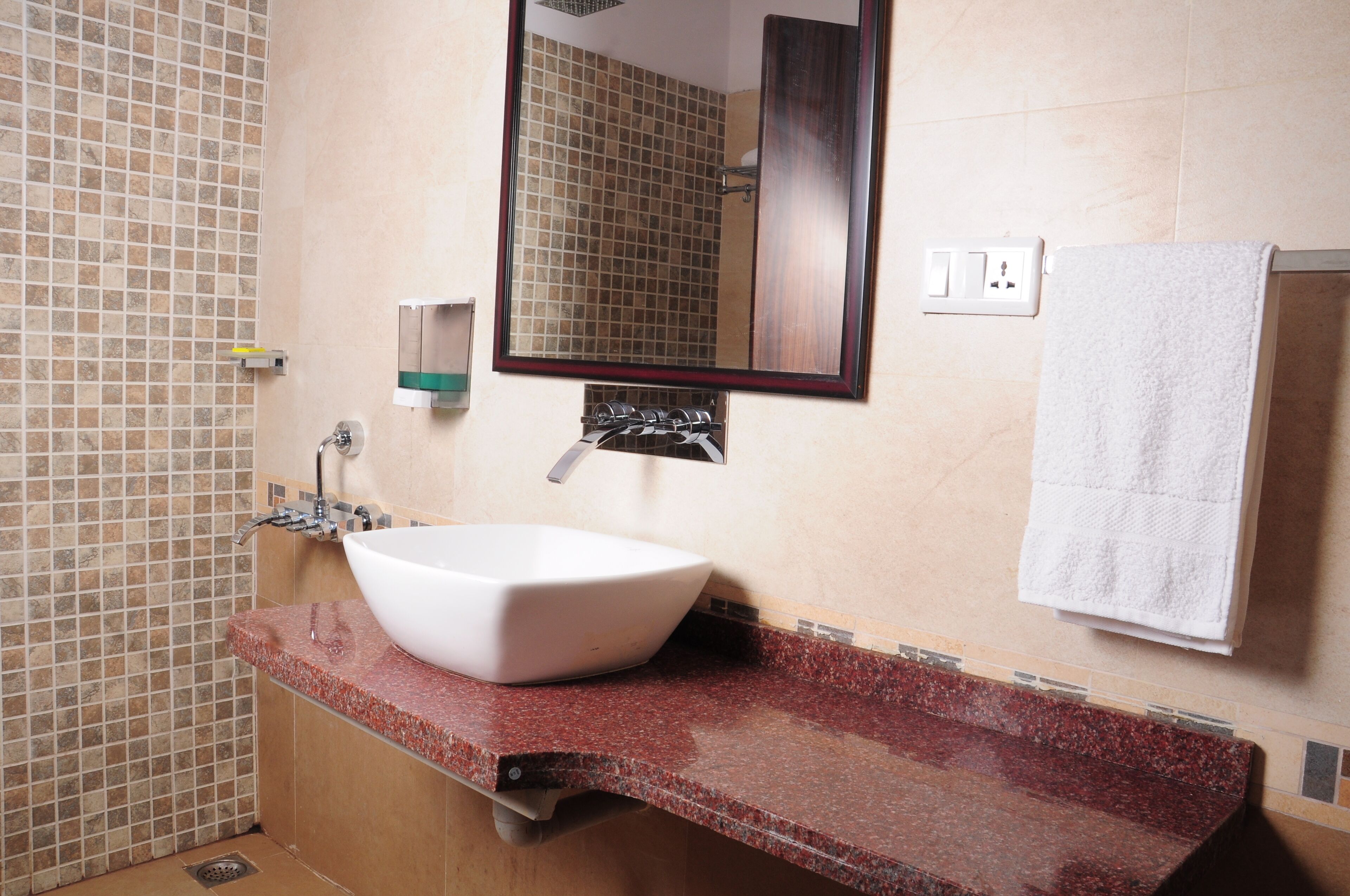 A bathroom with a white vessel sink, a mirror, and a towel rack.