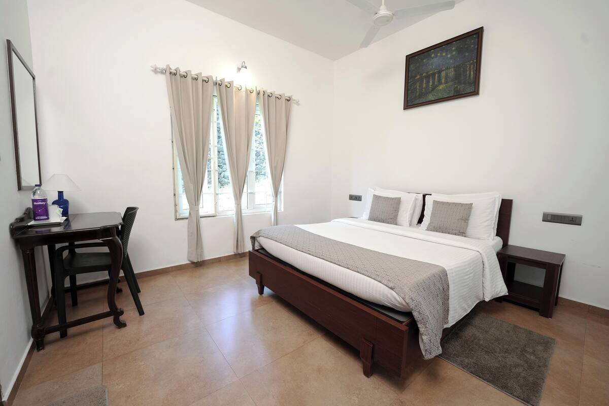A bedroom with a bed, a desk, and a chair.