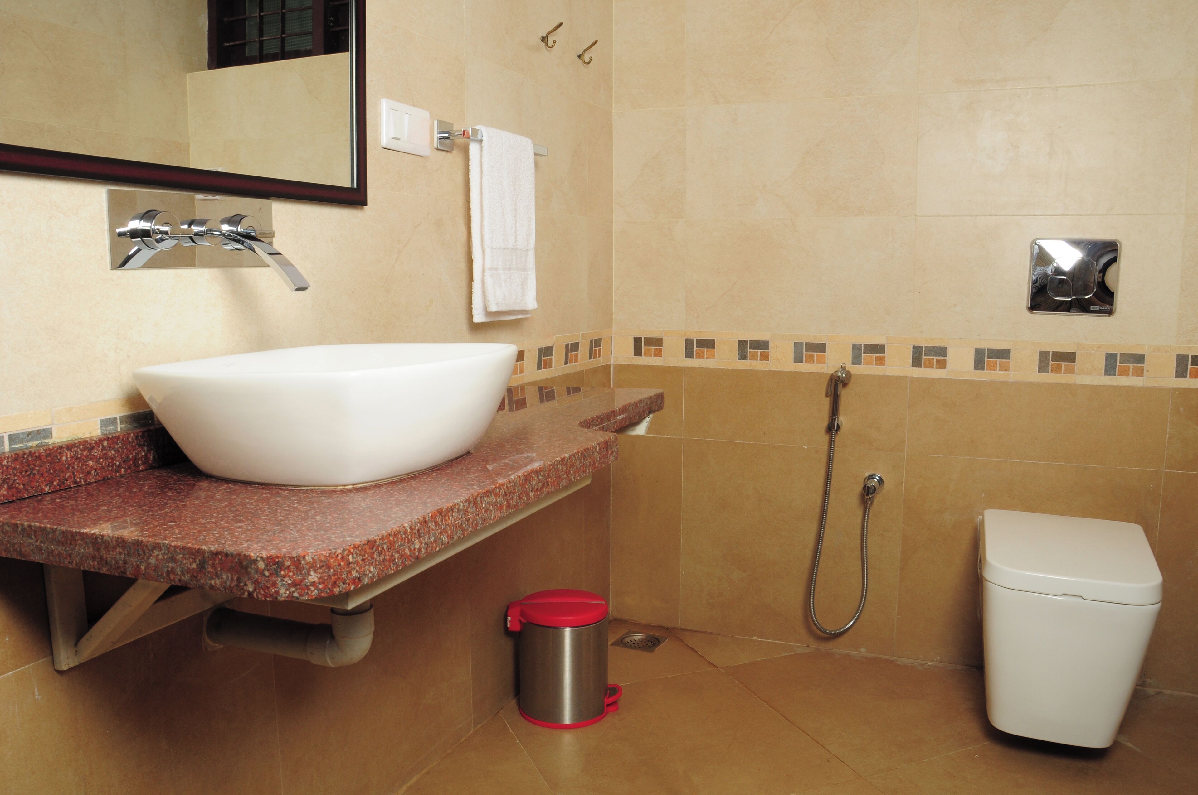 A bathroom with a white sink, a red trash bin, a shower, and a toilet.