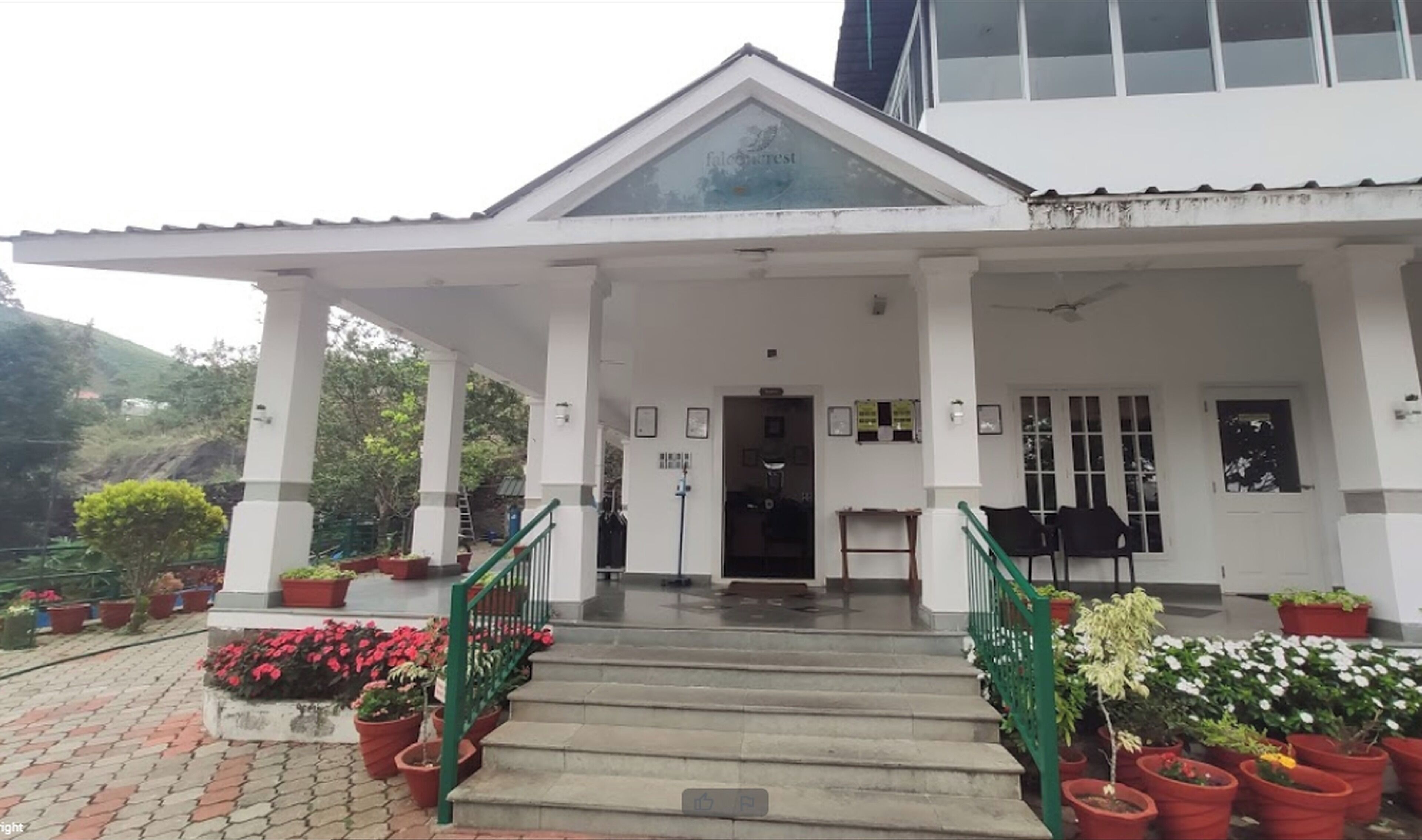 A building with a covered entrance, steps leading up to it, and potted plants around the entrance area.