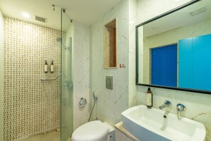 A bathroom with a glass-enclosed shower, a white sink with a mirror, and a toilet.