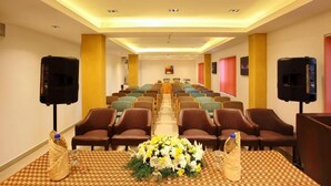 Una sala conferenze con file di sedie, un tavolo lungo con un centrotavola floreale e due altoparlanti su supporti.