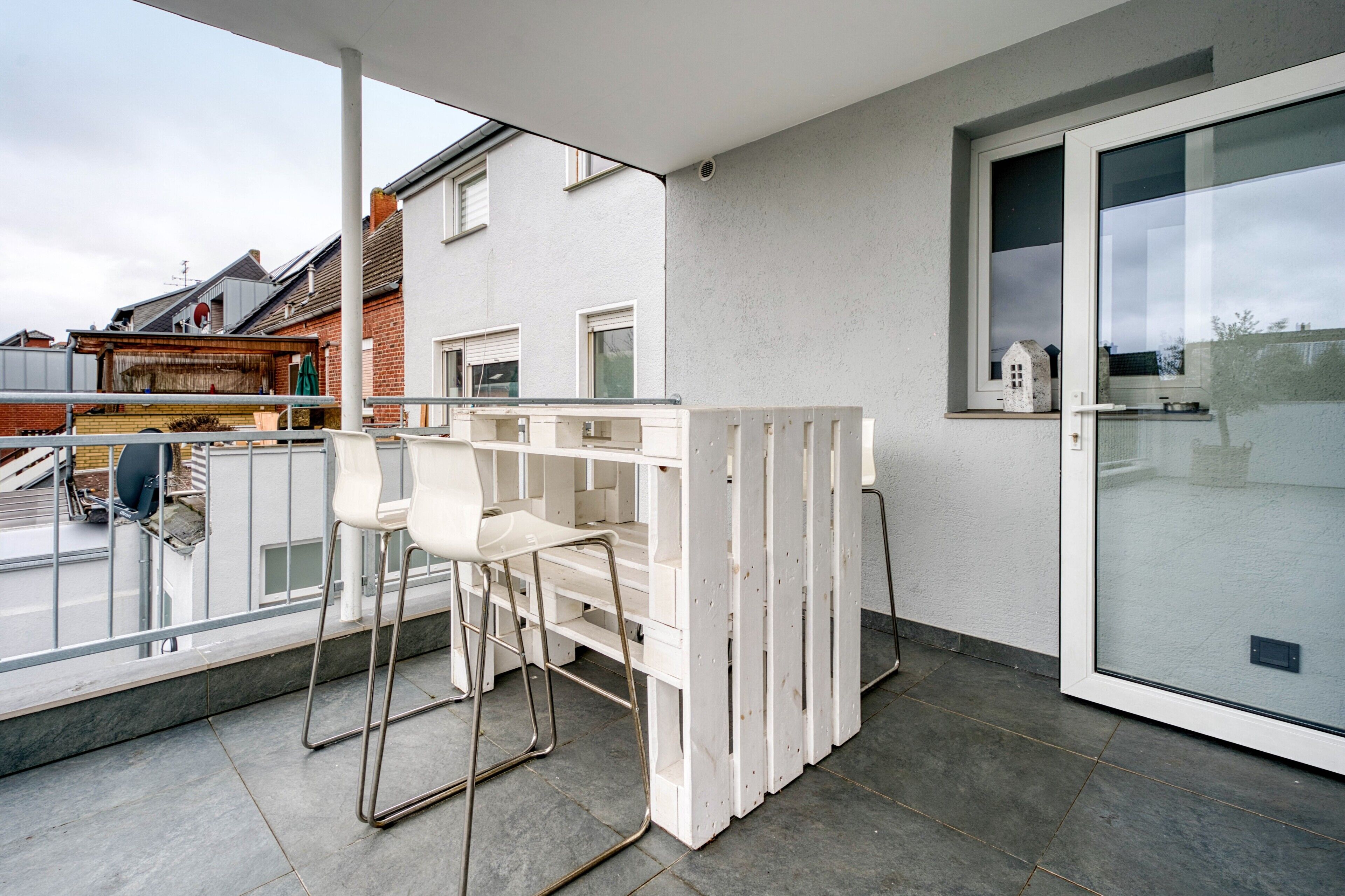 A balcony with a white railing, two white chairs, and a small table.