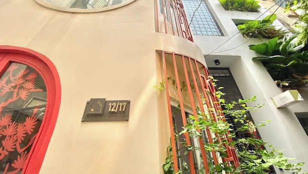 A building with a unique architectural design, featuring circular windows and a red door. - Cherry Blossom Boutique Hotel NTMK (Ho Chi Minh City)