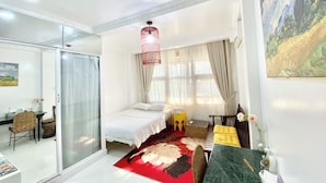 A modern bedroom with a bed, a sofa, a dining table, and a glass partition. - Cherry Blossom Boutique Hotel NTMK (Ho Chi Minh City)