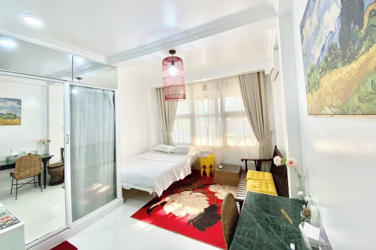 Een moderne slaapkamer met een bed, een sofa, een eettafel en een glazen scheidingswand.