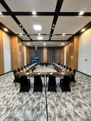 A conference room with a long table, chairs, a flat-screen TV, and a wooden accent wall. - Prime UMY Hotel Convention & Dormitory (Kasihan)