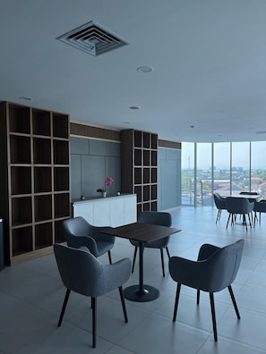 A modern interior with a dining area, built-in shelving, and a large window offering a city view. - Prime UMY Hotel Convention & Dormitory (Kasihan)