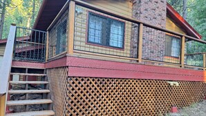 Une cabane dotée d’une terrasse en bois, d’un escalier et d’un balcon grillagé.
