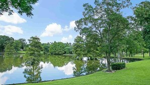 A serene park with a pond, trees, and a grassy area.