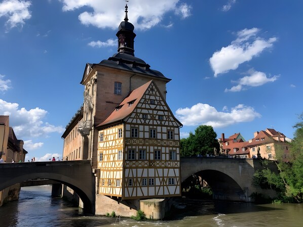 Un bâtiment à colombages doté d’une tour, d’un pont et bordé par une rivière.