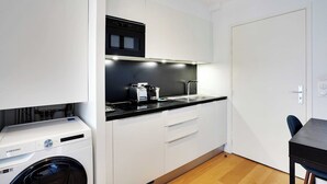 Une cuisine compacte équipée d’un lave-linge, d’un micro-ondes noir et d’un évier.
