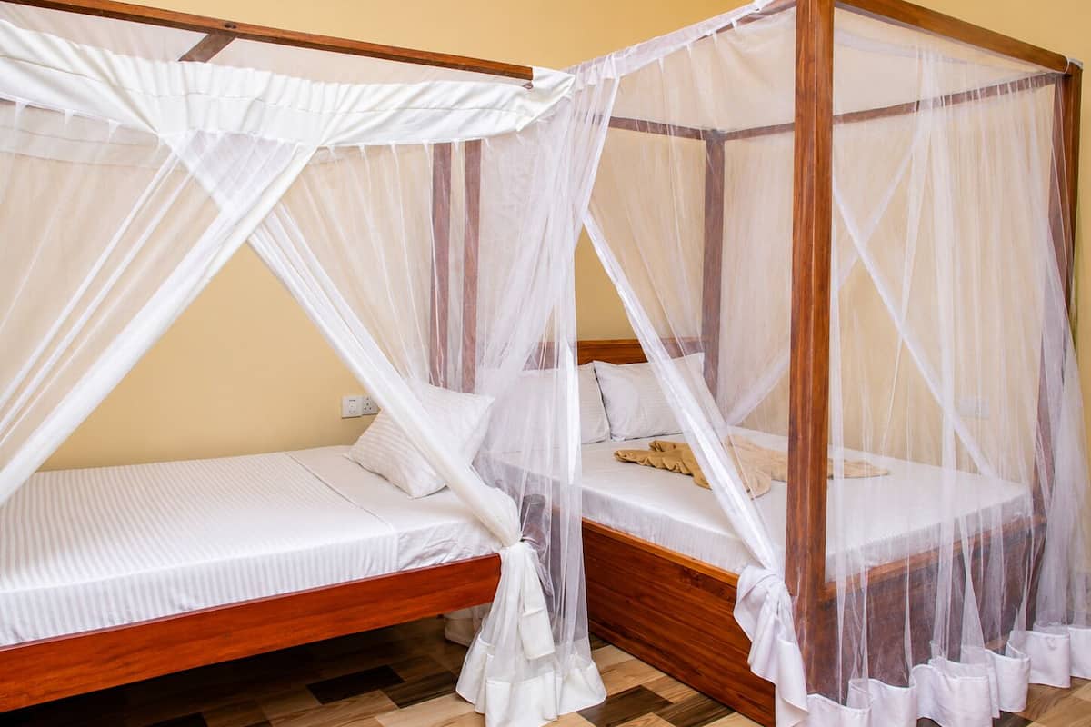 Una habitación con dos camas de madera, cada una con dosel y almohadas.