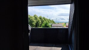 A view from a window with a view of trees and a wind turbine in the distance. - Lovingly converted 90 sqm attic apartment. Experience idyllic Selfkant. (Heinsberg)