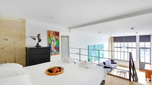 A modern hotel room with a large bed, a desk, and a balcony with a view.