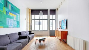 A modern living room with a grey sofa, a small round table, and a wooden cabinet.