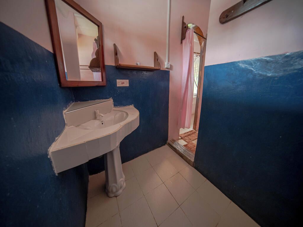 A bathroom with a sink, mirror, and a door leading to another room.