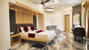 Een moderne hotelkamer met een bed, nachtkastje, stoel en een grote spiegel.