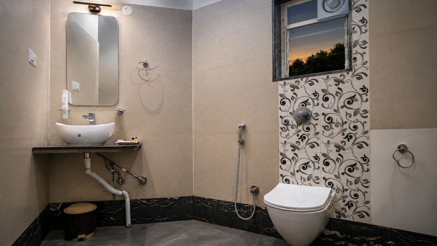Une salle de bain équipée d’un lavabo, d’un miroir, de toilettes, d’une douche et de carreaux décoratifs sur les murs.