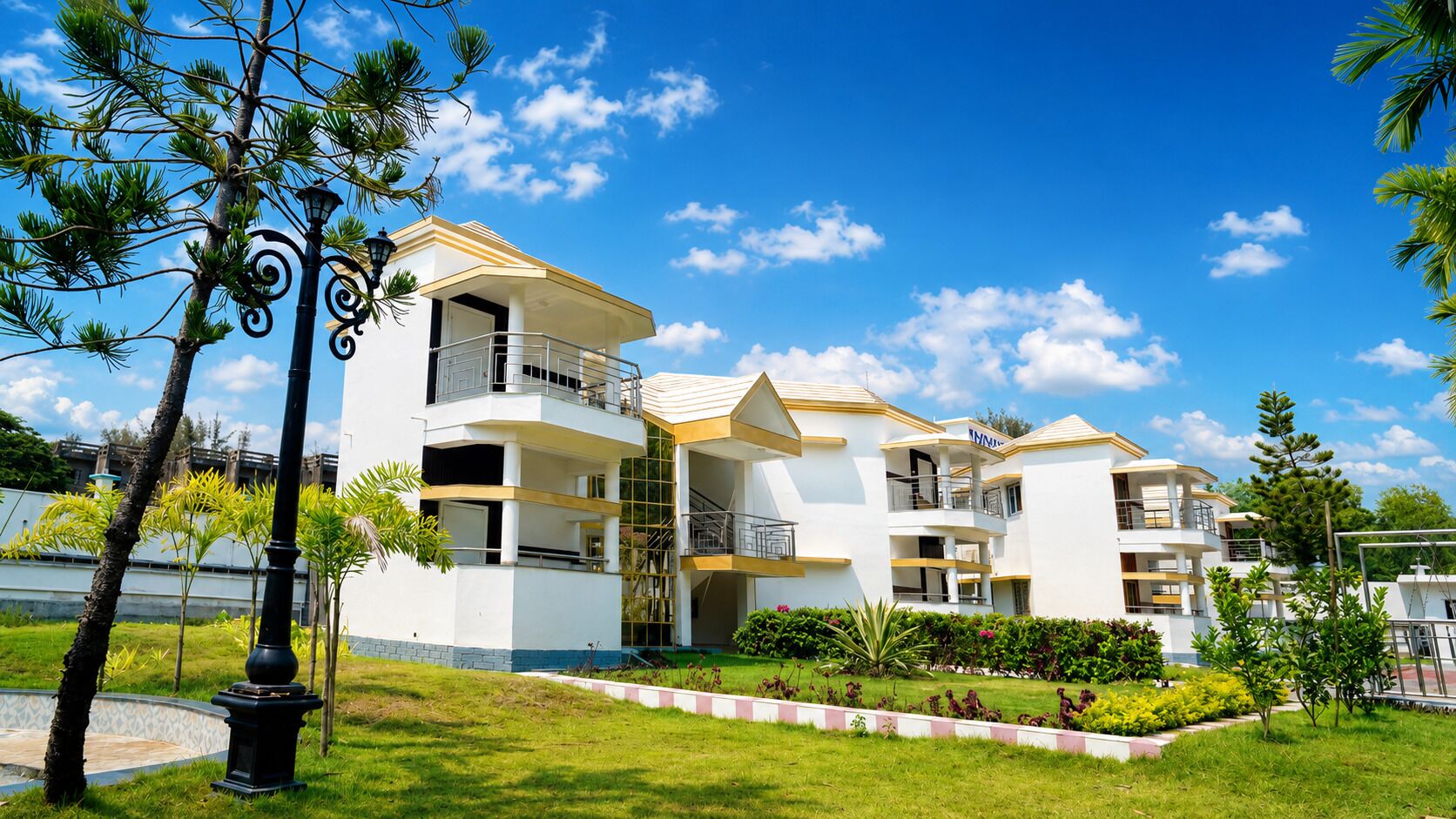 A multi-story residential building with balconies, a well-maintained lawn, and a clear blue sky.