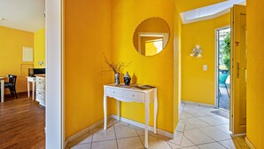 A room with yellow walls, a white desk with drawers, a round mirror, and a door leading outside. - Apartment '7' with Wi-Fi (Neuenkirchen)