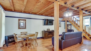 Un vaste espace de vie doté d’un plafond en bois, d’une table à manger avec des chaises, d’un canapé et d’un escalier.
