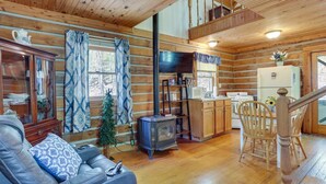 Ein gemütliches Blockhaus-Interieur mit Kamin, Holzmöbeln, Essbereich und Küche.