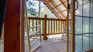 Ein Dachzimmer mit einer Holzterrasse, einem Fenster mit Milchglas und einer Tür mit Griff.