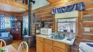 Ein gemütliches Cabin-Interieur mit Holzvertäfelung, einer Essecke, einer Küche inklusive Herd, Mikrowelle und einer Kaffeestation.