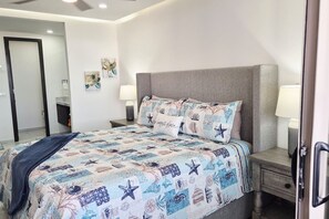 A bedroom with a bed, nightstands, and wall art.