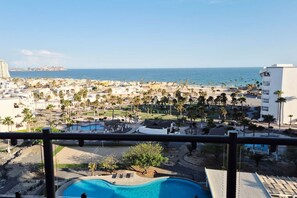 Un complexe hôtelier doté d’une piscine, de palmiers et offrant une vue sur l’océan.