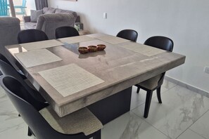 Une table à manger avec quatre chaises, une plante au centre et un canapé à l’arrière-plan.