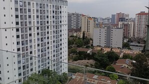 A high-rise residential building with multiple balconies, surrounded by other residential buildings and greenery.