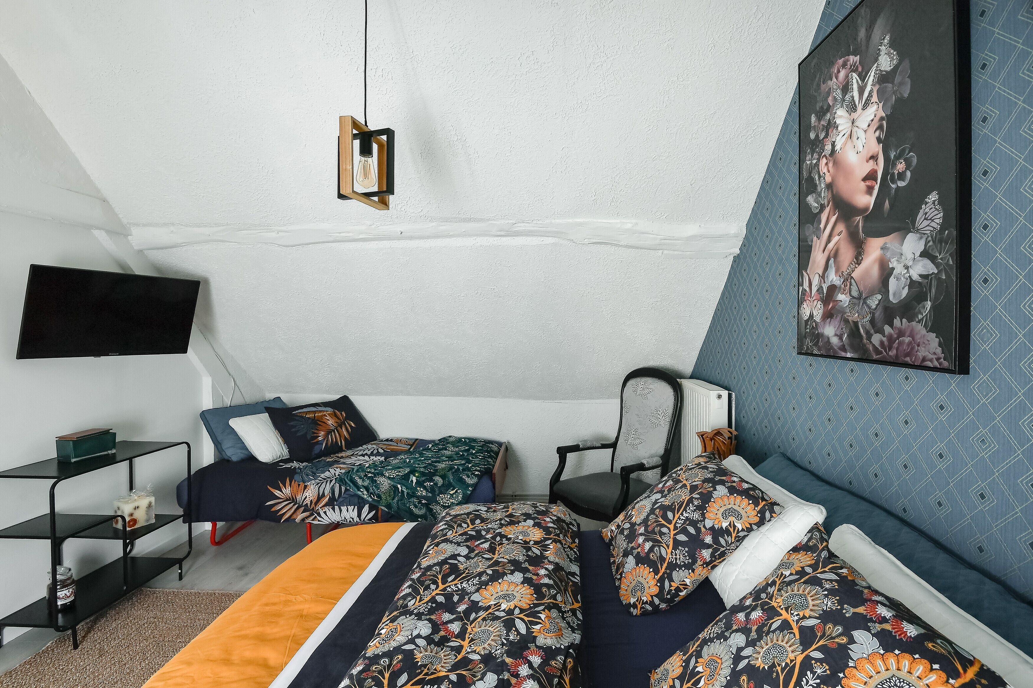 A bedroom with a bed, a chair, a TV, and a painting on the wall.