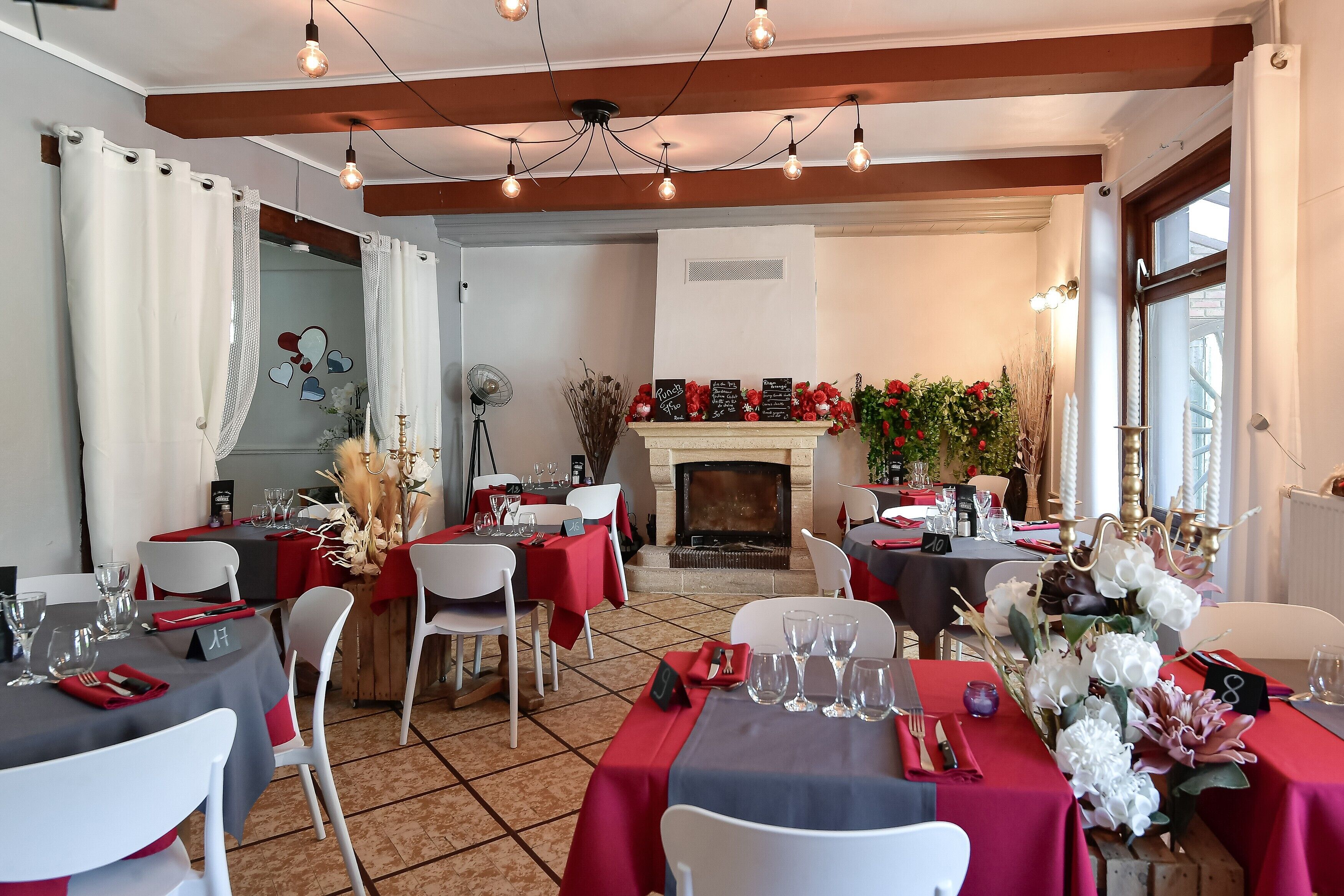 Un espace repas avec des tables dressées, une cheminée et une vue sur l’extérieur.