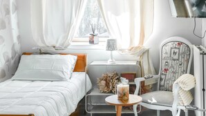 Ein Schlafzimmer mit Bett, Nachttisch, Sessel und einem an der Wand befestigten Fernseher.