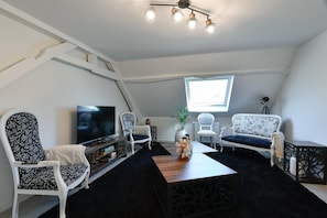 A modern living room with a TV, two sofas, a coffee table, and a ceiling fan.