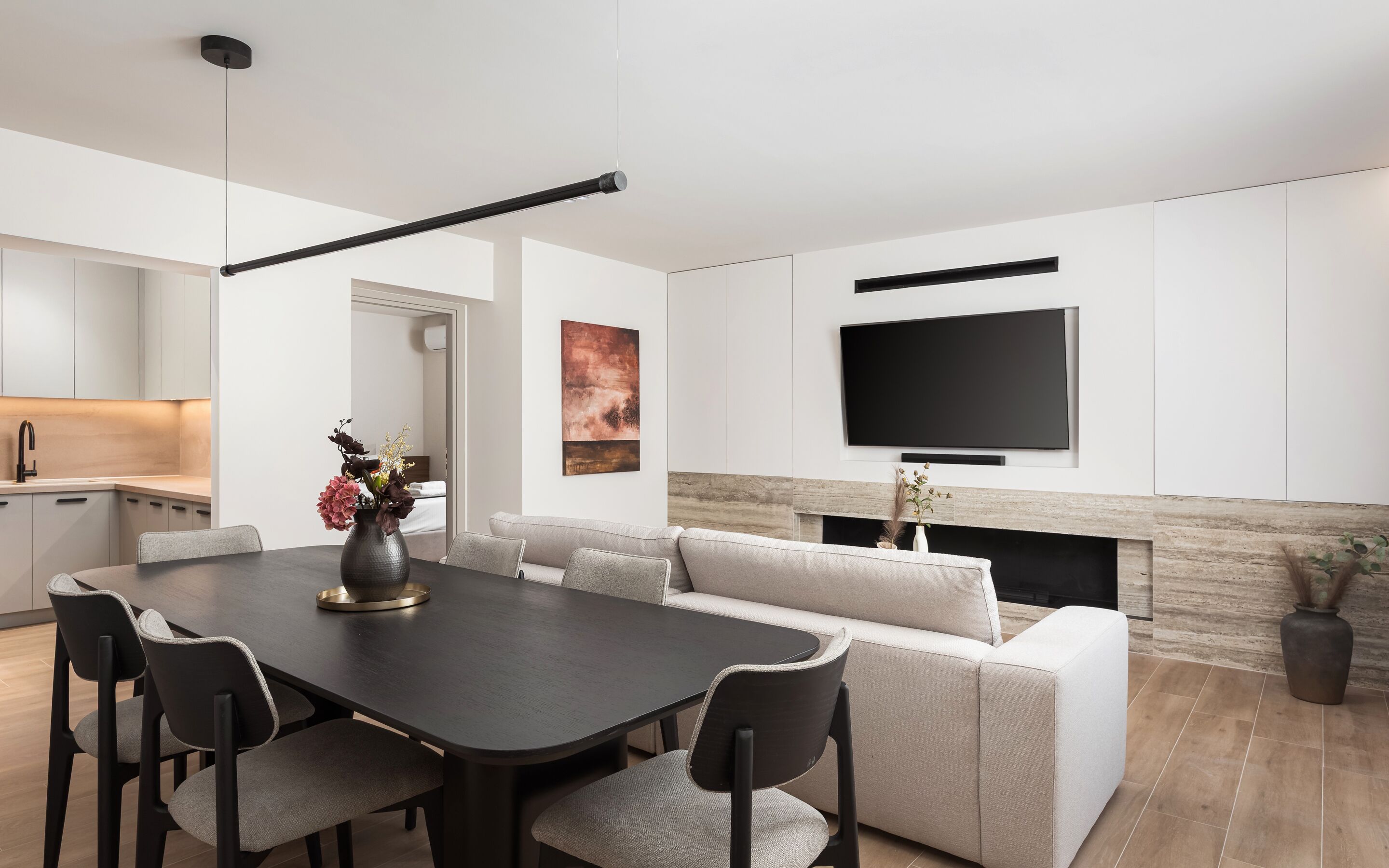 Un salon moderne comprenant un canapé, une table à manger avec des chaises, un téléviseur à écran plat fixé au mur et une cheminée.