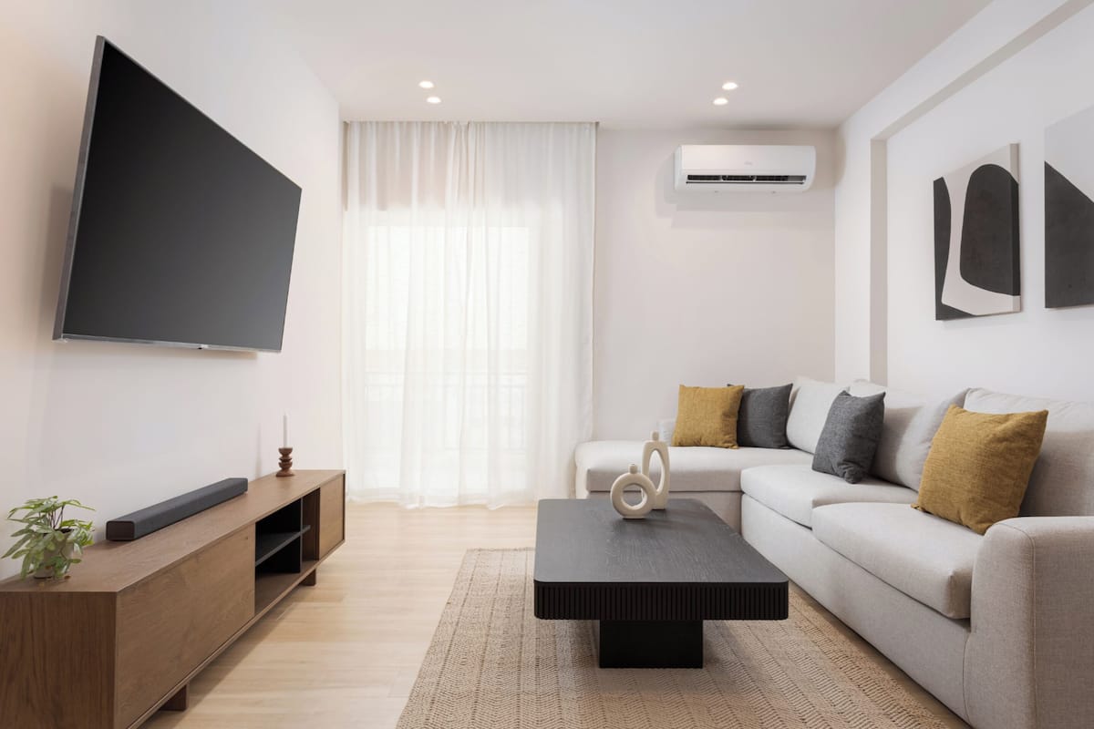 A modern living room with a flat-screen TV, a sofa, a coffee table, and a wooden entertainment unit.