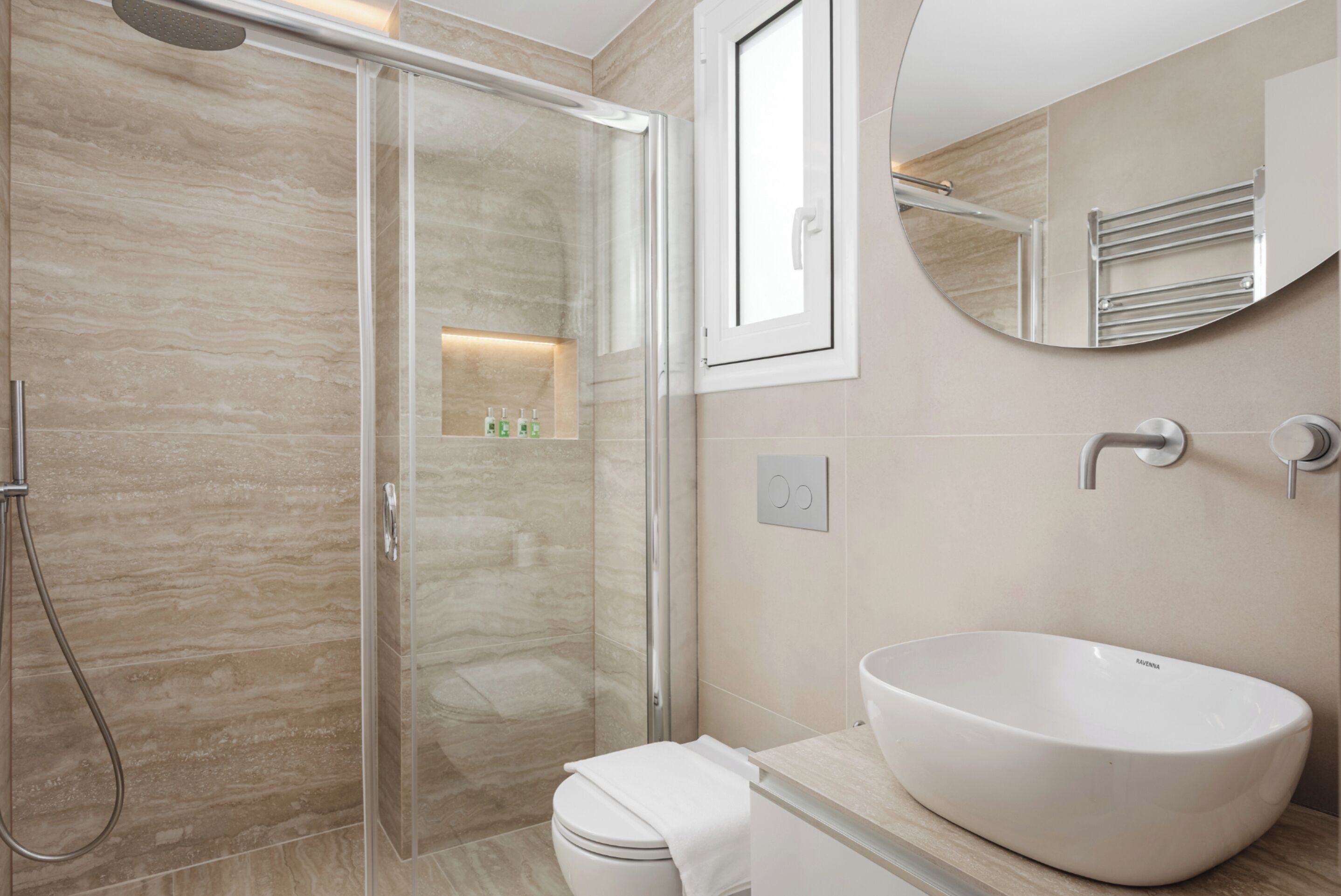 Un baño moderno con cabina de ducha de vidrio, un lavabo blanco y un inodoro.