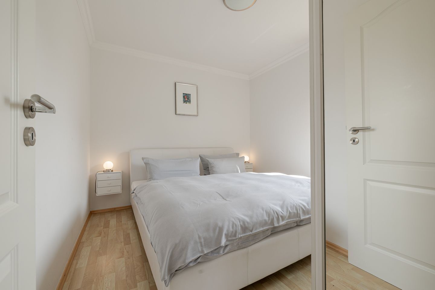 A bedroom with a bed, bedside tables, and a door.