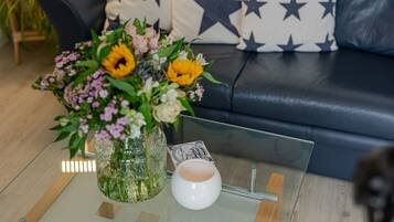 Et sofabord af glas med en vase med blomster og et hvidt lys.