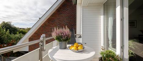 A balcony with a round table, potted plants, and a bowl of lemons.