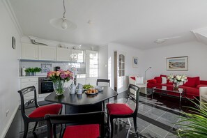 Un salon moderne avec un canap é rouge, une table à manger avec des chaises et un coin cuisine doté de meubles blancs.