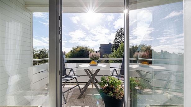 A balcony with a table and chairs, a potted plant, and a view of the sky and buildings. - Strand - Lust auf Sylt - Apartment Strand for 2 persons (Sylt-Ost)